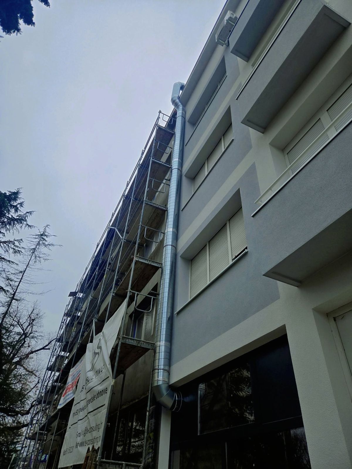 Vertikalni spiro kanal uz fasadu višekatne poslovne zgrade, rad s dizalice